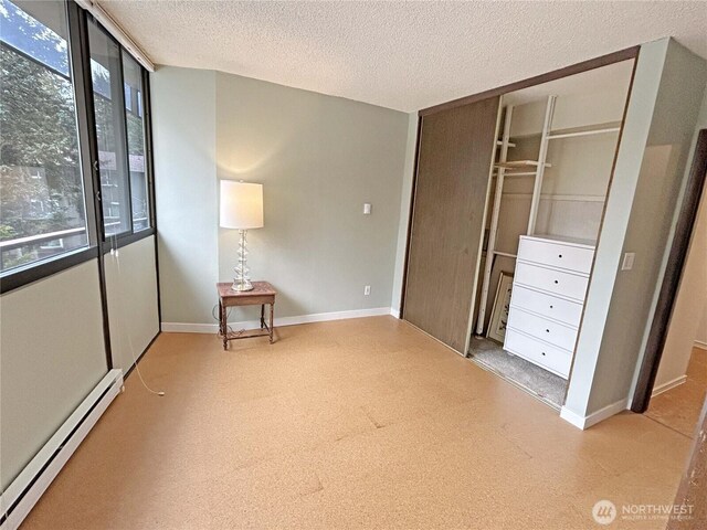 unfurnished bedroom with baseboards, a closet, a baseboard heating unit, and a textured ceiling