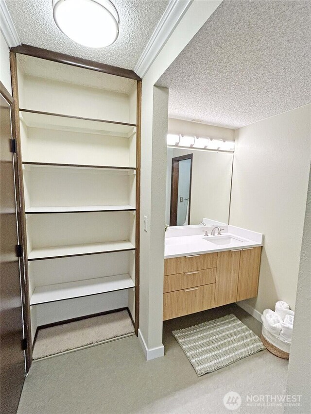 bathroom featuring baseboards, a textured ceiling, and vanity