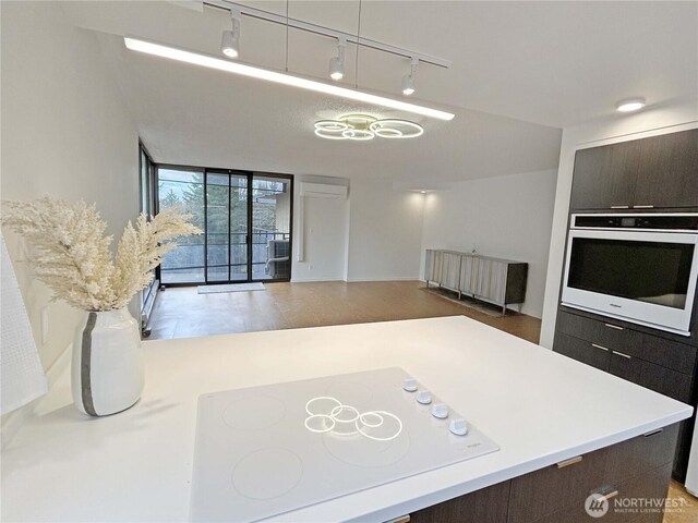 kitchen featuring white appliances, open floor plan, light countertops, dark brown cabinets, and expansive windows