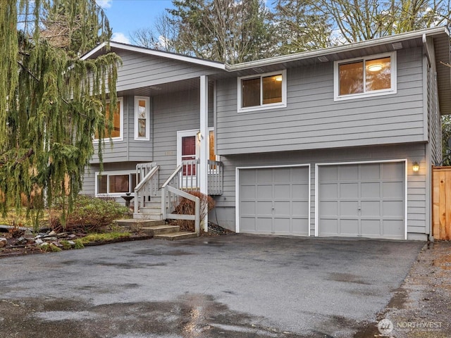 split foyer home featuring an attached garage and aphalt driveway