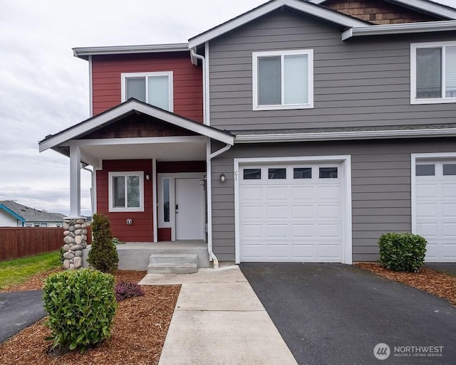 view of front of home featuring a garage, driveway, and fence