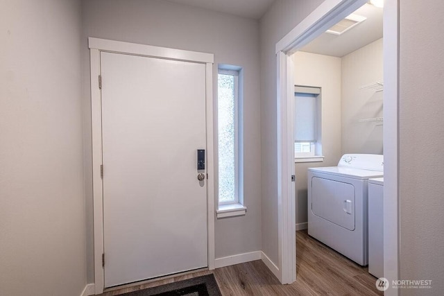 clothes washing area featuring light wood-type flooring, laundry area, washer and clothes dryer, and baseboards