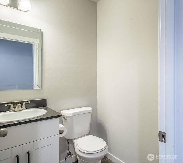 bathroom featuring vanity, toilet, and baseboards