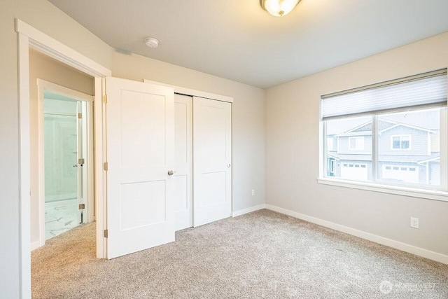 unfurnished bedroom featuring a closet, light colored carpet, and baseboards