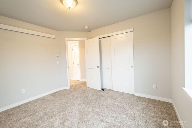 unfurnished bedroom featuring light carpet, a closet, and baseboards