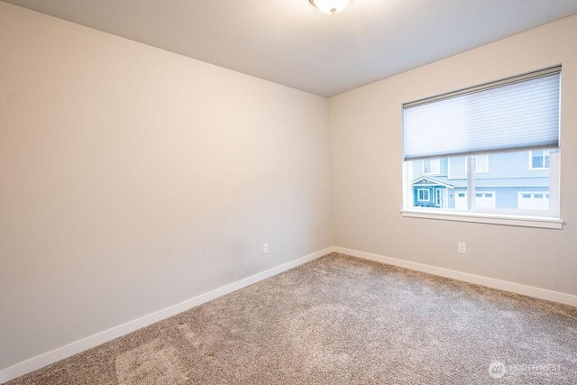 spare room featuring carpet and baseboards