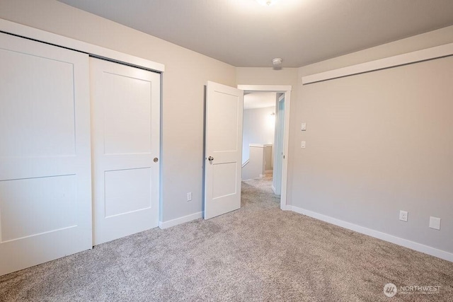 unfurnished bedroom with baseboards, a closet, and light colored carpet