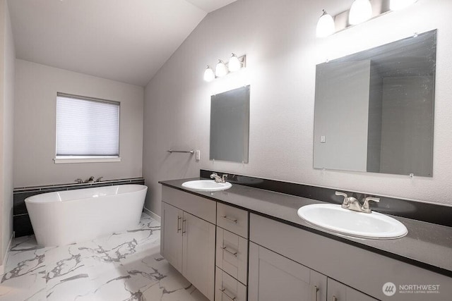 bathroom featuring double vanity, a soaking tub, vaulted ceiling, and a sink