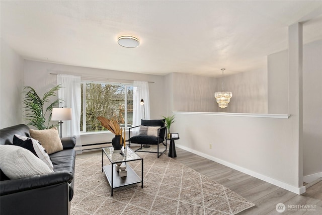 living room with a baseboard heating unit, baseboards, wood finished floors, and a chandelier