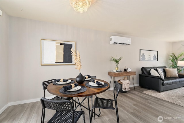 dining area with a chandelier, baseboards, light wood-style flooring, and a wall unit AC