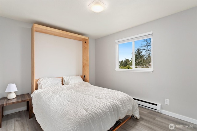 bedroom with baseboard heating, baseboards, and wood finished floors