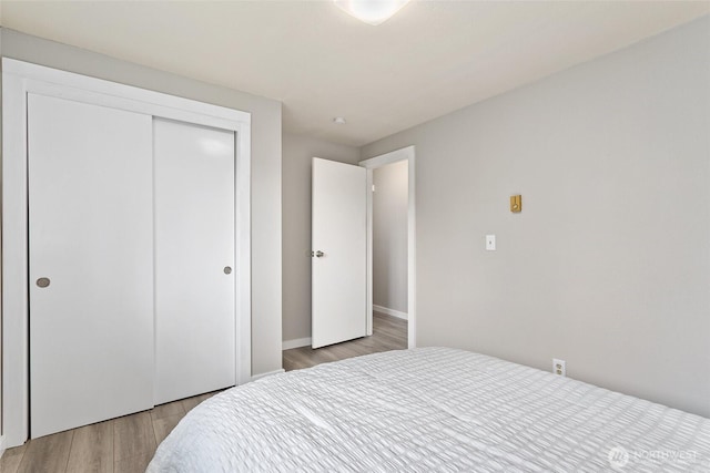 bedroom featuring a closet, light wood finished floors, and baseboards