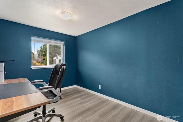 office space with a textured ceiling, baseboards, and wood finished floors