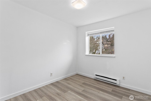 empty room featuring baseboard heating, baseboards, and wood finished floors