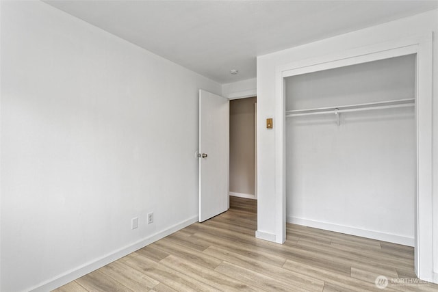 unfurnished bedroom with a closet, baseboards, and light wood finished floors