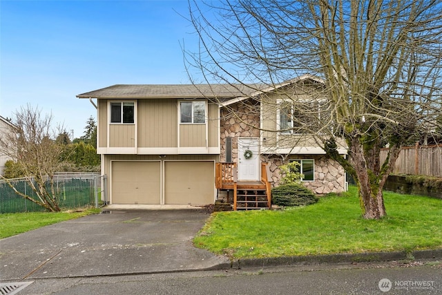 split foyer home with fence, driveway, an attached garage, a front lawn, and stone siding