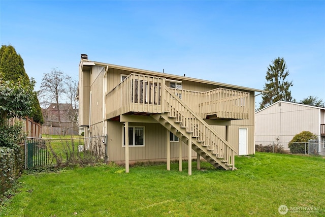 rear view of property featuring a deck, stairs, a yard, and fence