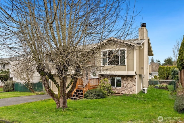 view of front of house with stone siding, a front yard, and fence