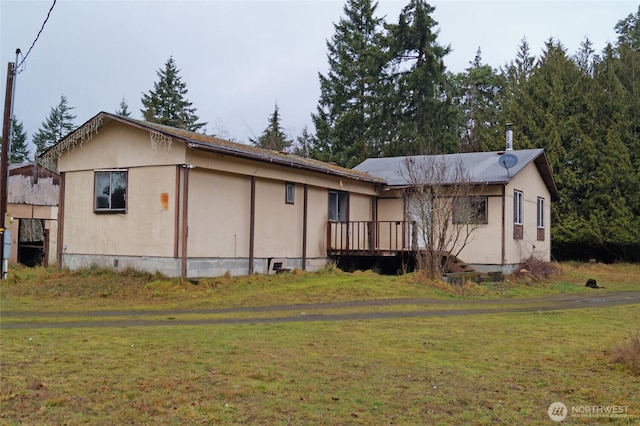 view of front of home with a deck and a front lawn