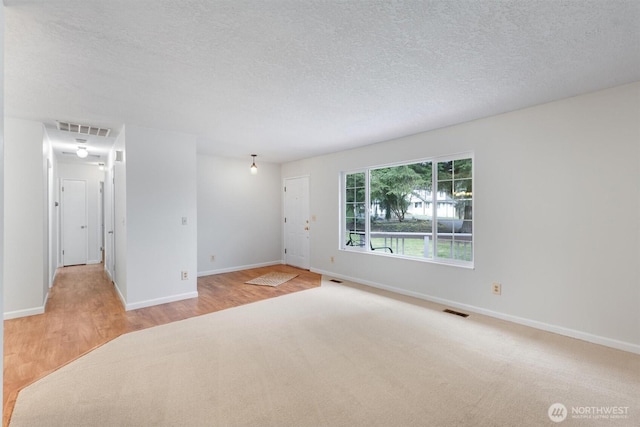 spare room with baseboards, visible vents, and a textured ceiling