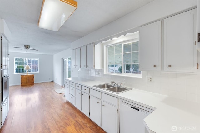 kitchen featuring oven, a sink, white cabinets, white dishwasher, and decorative backsplash