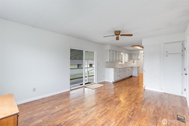 unfurnished living room with light wood-type flooring, baseboards, and ceiling fan