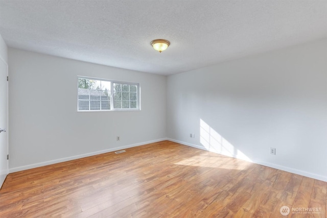 empty room featuring a textured ceiling, baseboards, and wood finished floors