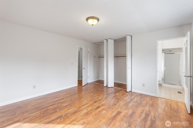 unfurnished bedroom with visible vents, baseboards, light wood-style floors, and ensuite bathroom