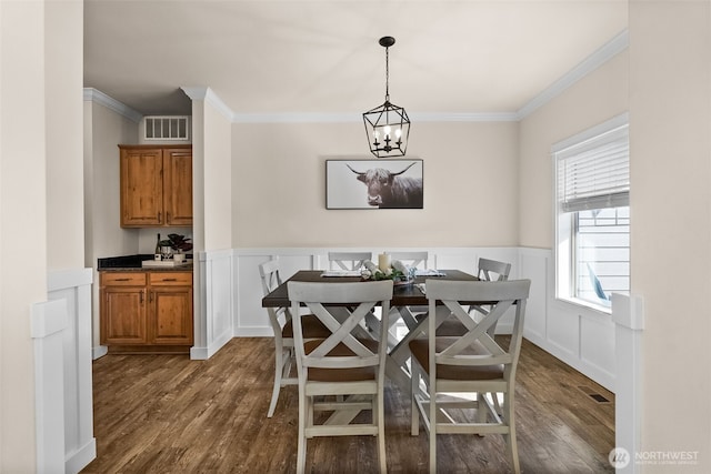 dining room featuring ornamental molding, dark wood-style flooring, visible vents, and an inviting chandelier