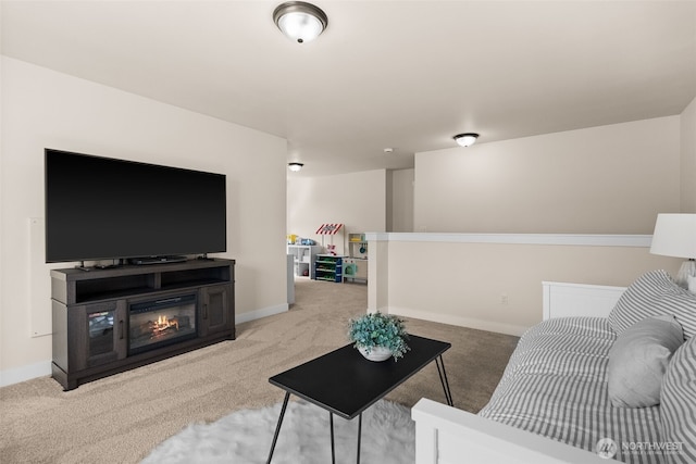 living room featuring a glass covered fireplace, carpet flooring, and baseboards