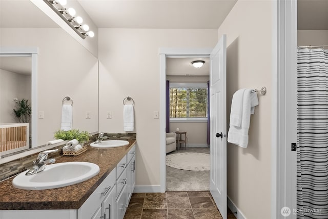 bathroom with double vanity, baseboards, and a sink