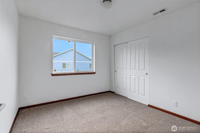 unfurnished bedroom with carpet floors, a closet, visible vents, and baseboards