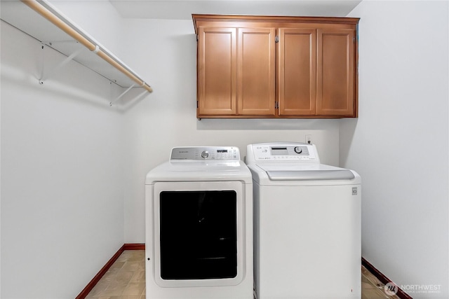 laundry area featuring separate washer and dryer, cabinet space, and baseboards