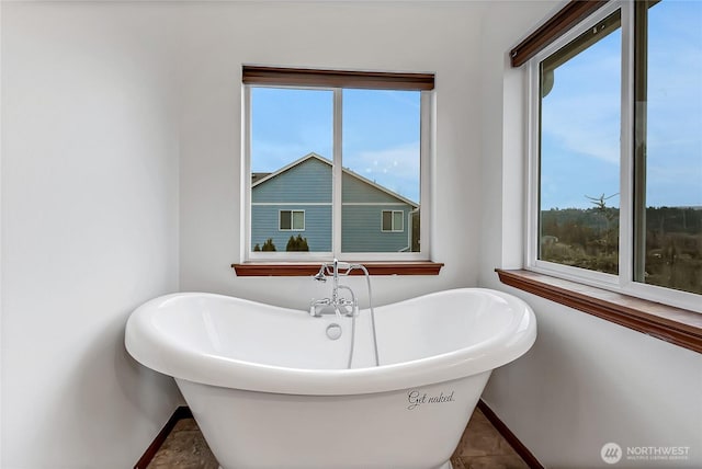 bathroom with a freestanding tub and baseboards