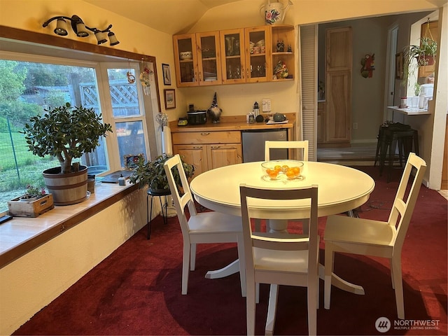 dining area featuring dark colored carpet and vaulted ceiling