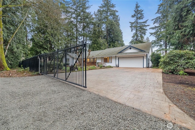 ranch-style house with an attached garage, fence, and decorative driveway