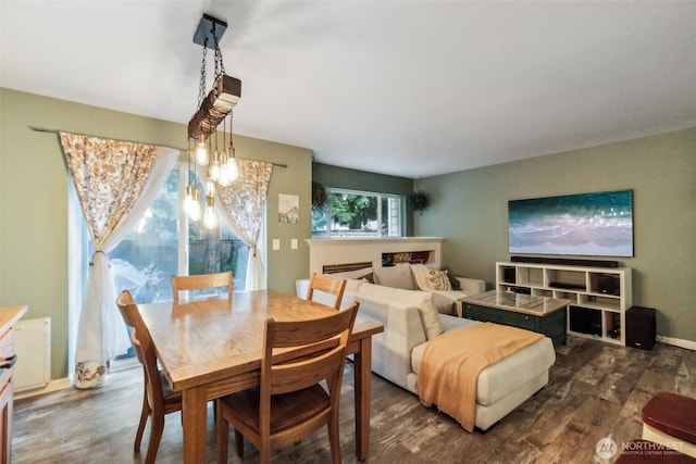 dining area with a fireplace, baseboards, and dark wood-type flooring