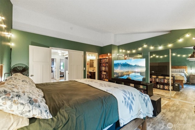 bedroom with light wood-type flooring and lofted ceiling