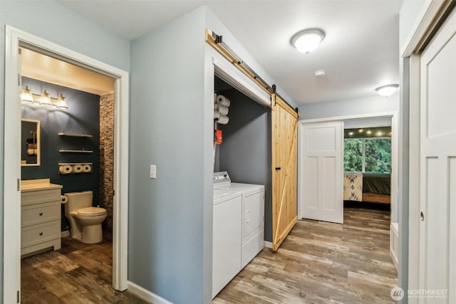 laundry area with laundry area, a barn door, baseboards, dark wood-style floors, and separate washer and dryer