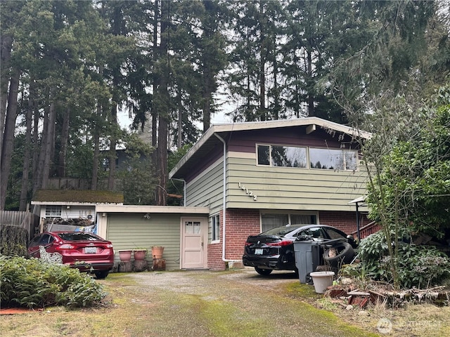 view of front of house with dirt driveway, brick siding, and a front yard