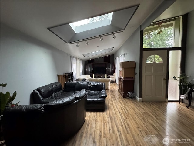 living room featuring lofted ceiling with skylight, wood finished floors, and track lighting