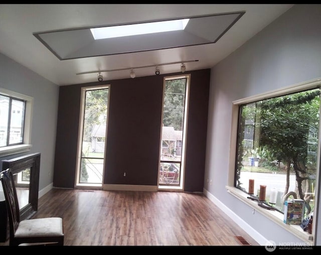 interior space with a skylight, baseboards, and wood finished floors