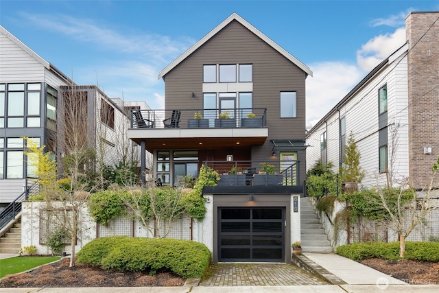 view of front of property with stairway, driveway, a balcony, and an attached garage