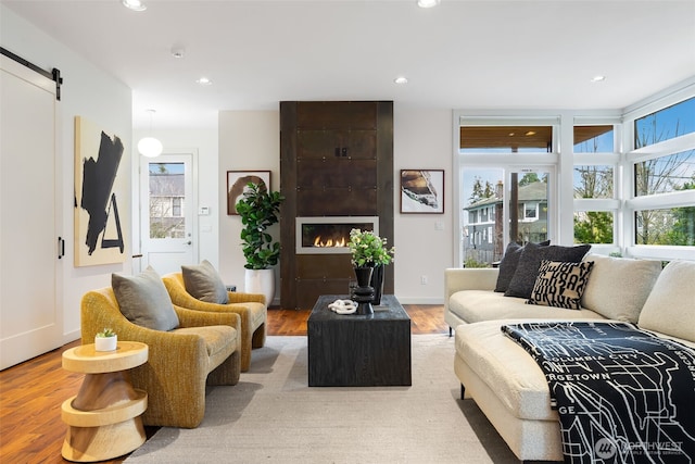 living room with recessed lighting, wood finished floors, a fireplace, and a barn door