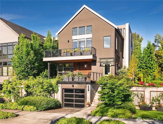 contemporary home with driveway, a garage, stairway, and a balcony