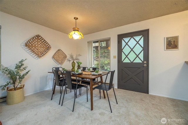 dining space featuring a textured ceiling, baseboards, and light colored carpet