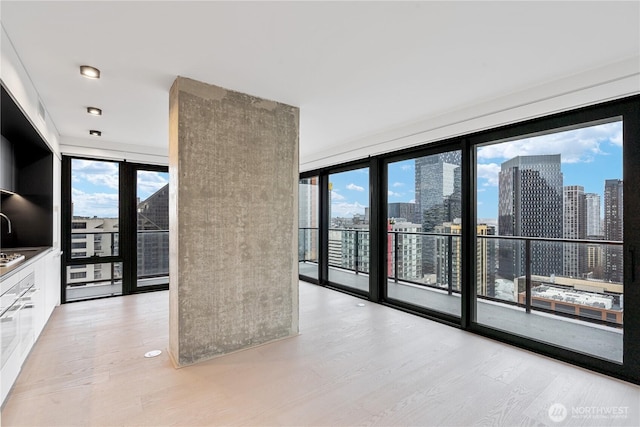 interior space featuring a view of city, plenty of natural light, light wood-style flooring, and white cabinets