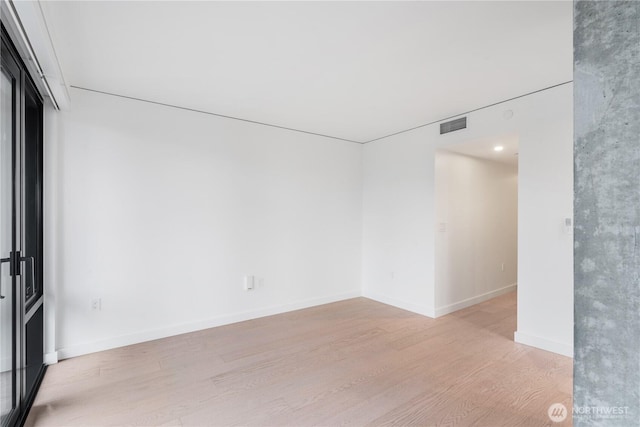 spare room featuring light wood-type flooring, baseboards, and visible vents