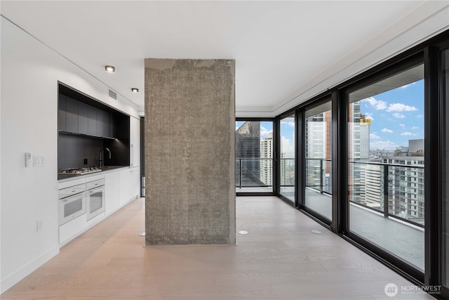 interior space with light wood finished floors, baseboards, a view of city, and visible vents