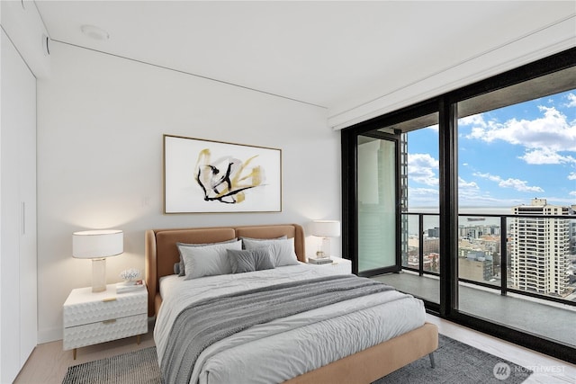 bedroom featuring access to outside, floor to ceiling windows, and a city view